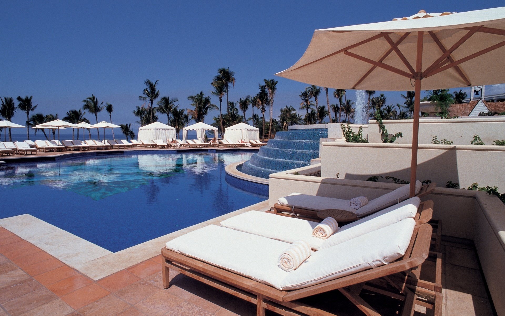 sonniger himmel sonnenliegen sonnenschirme schwimmbad wasser himmel resort erholung liegestühle palmen tropen brunnen hotel sommer hitze blauer himmel hitze
