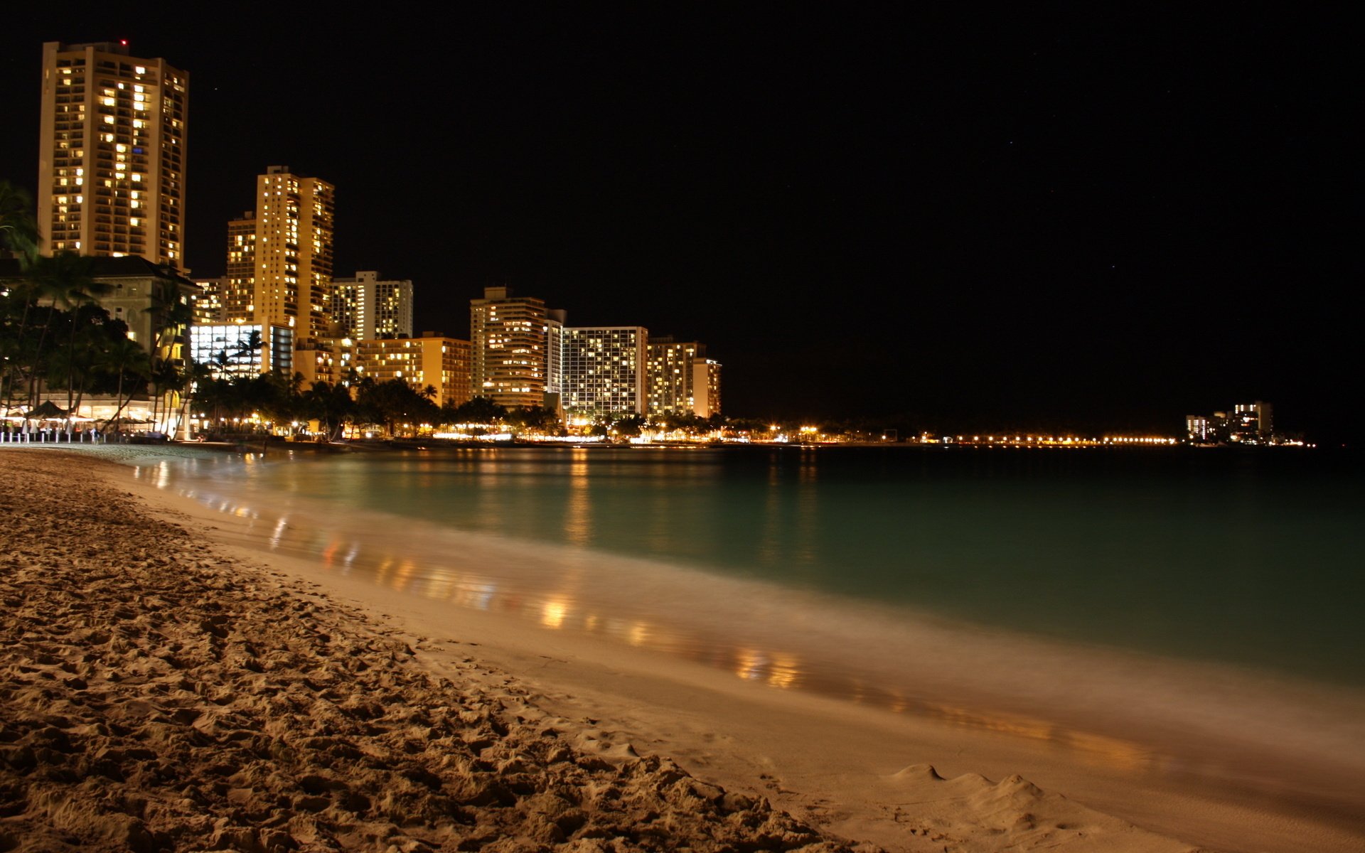 spiaggia vicino alla città grattacieli di notte sera luci silenzio grattacieli luce mare acqua costa sabbia alberi città notte luci della città