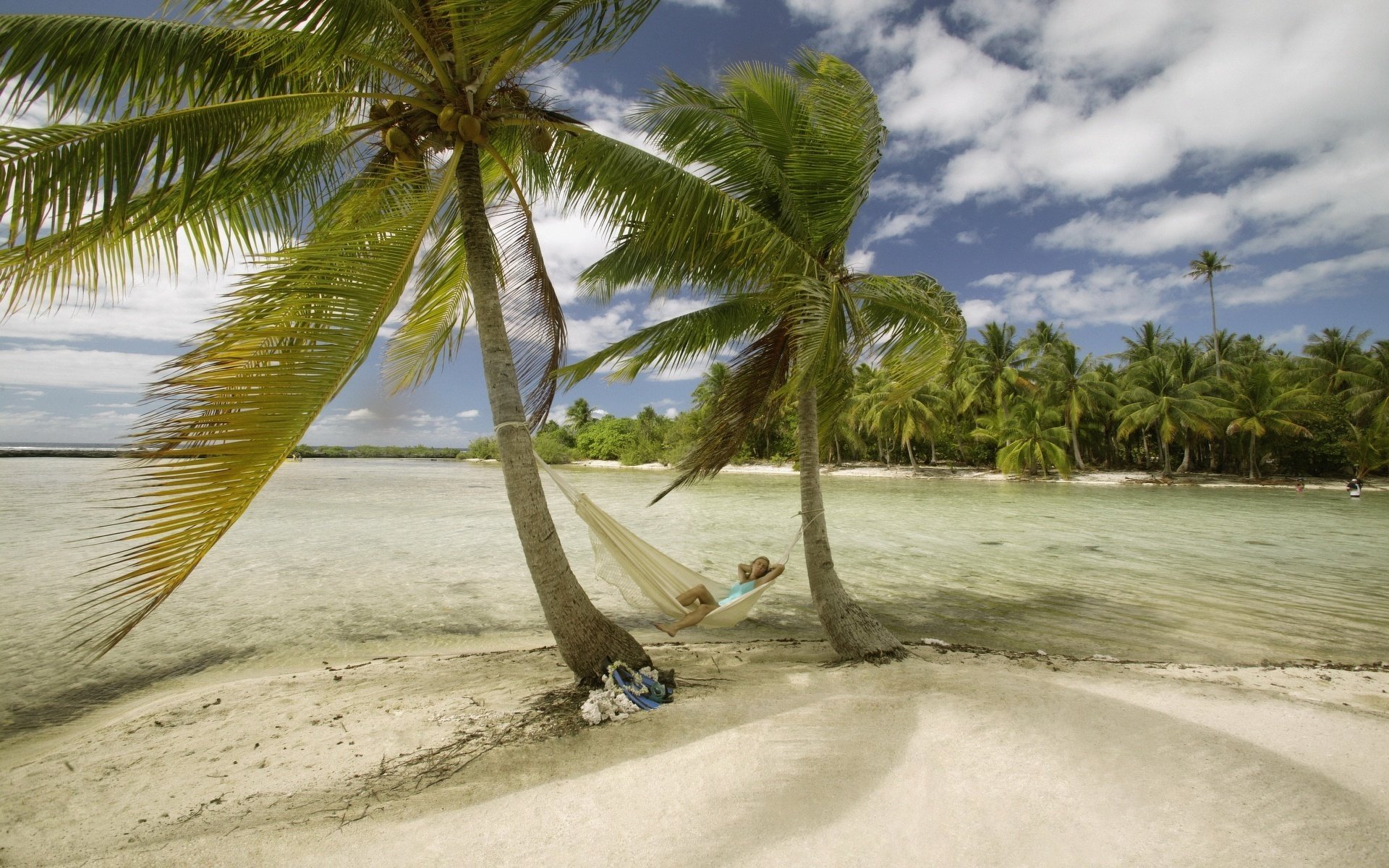 light breeze light sand hammock beach water sky sand palm trees girl vacation resort vacation paradise sea tropics island summer heat heat clouds vegetation nature landscape