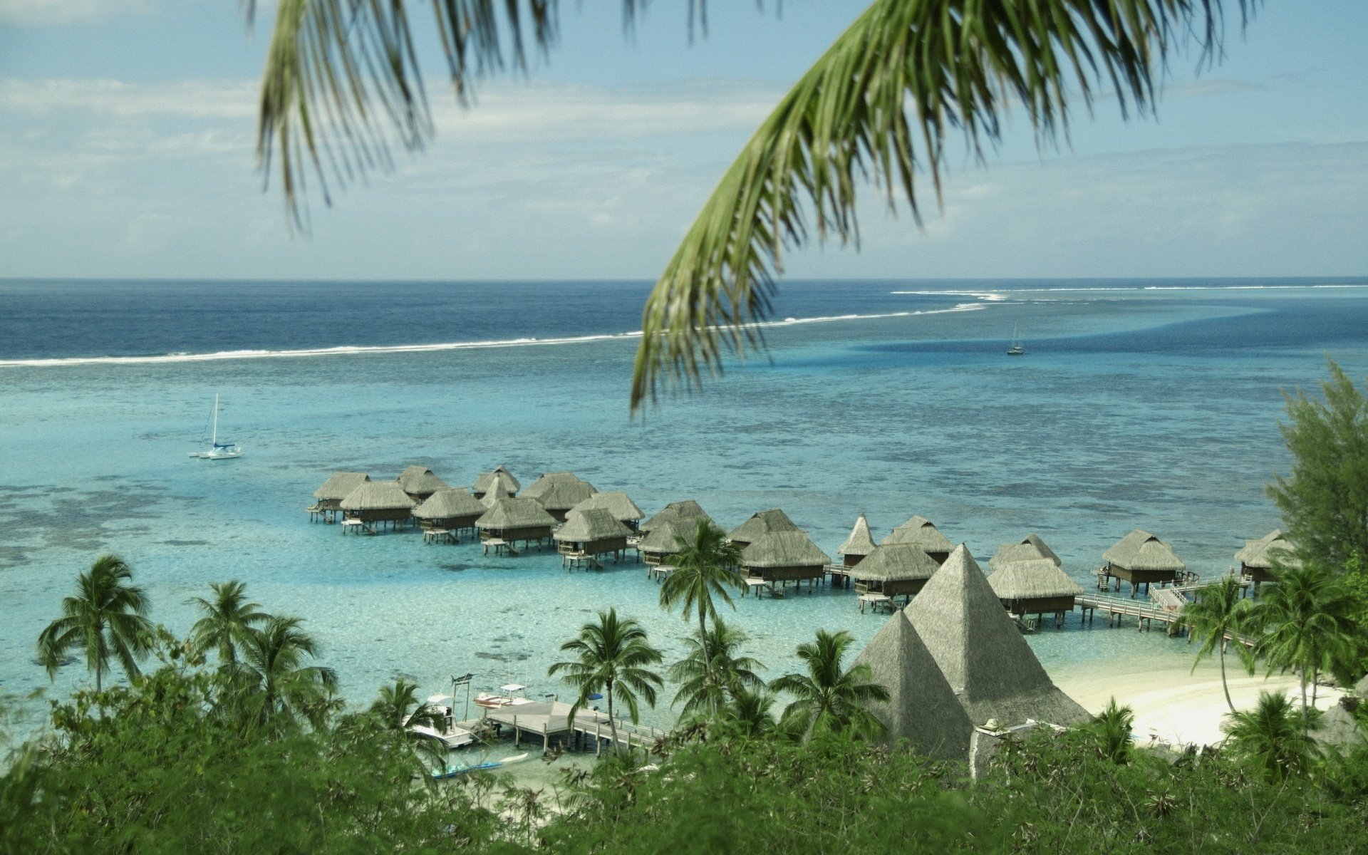 strohhäuser meerwasser küste strand wasser himmel tropen inseln natur meer landschaft ansicht höhe palmen vegetation ozean zweige brise paradies sommer hitze hitze resort yacht segelboot