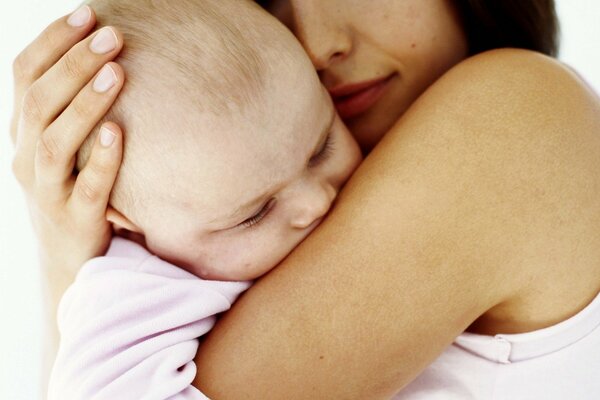 Das Baby, das auf den Armen seiner Mutter schläft. Mütterliche Zärtlichkeit