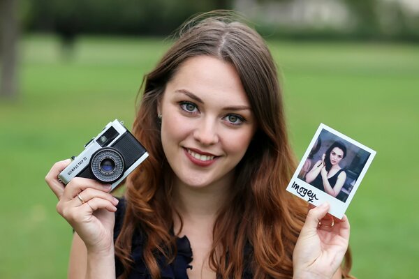 A smiling girl with a photo and a photo accessory in her hands