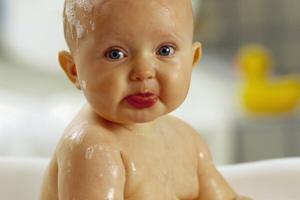 Piccolo bambino seduto nella vasca da bagno in schiuma di sapone