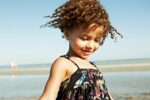 Fille avec des boucles au bord de la mer. Sourire de fille
