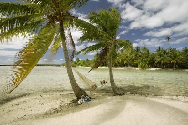 A girl on a hammock under palm trees at the resort