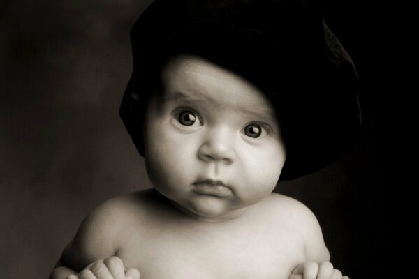 A child in a black hat looks surprised