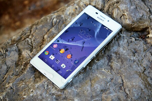 Biały smartfon Sony leży na mokrej skale