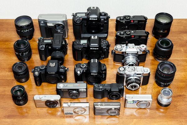 Kolekcja starych aparatów i obiektywów na drewnianym tle