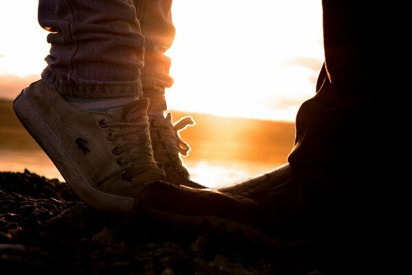 Deux paires de chaussures-elle et lui sur fond de coucher de soleil
