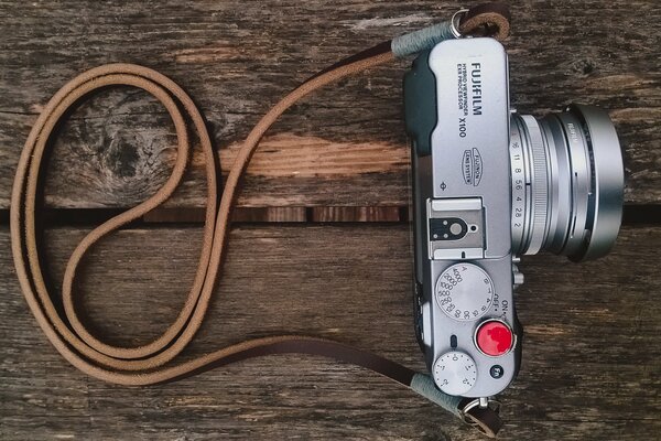 Fotocamera con cinturino su sfondo in legno