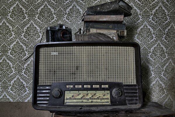 Auf einem alten Radio sind Bücher und eine Kamera zu sehen