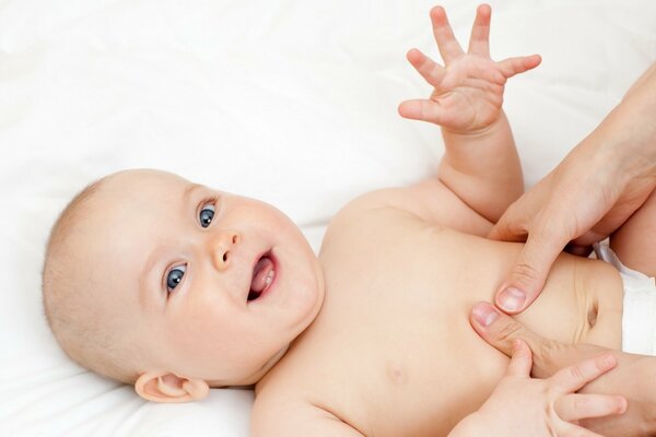 Mignon bébé souriant et les mains de maman sur son ventre