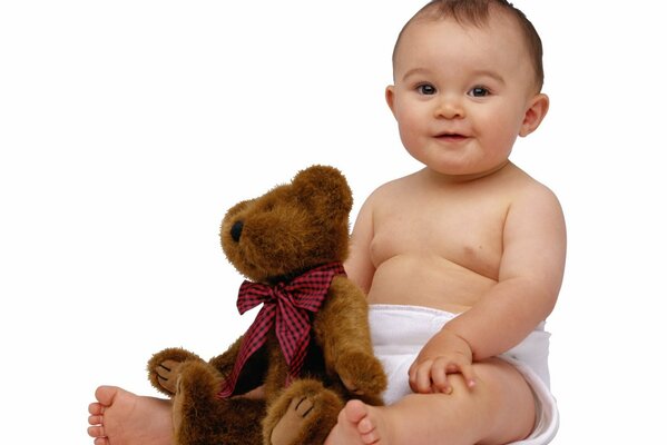 Süßes Baby mit Teddybär in der Nähe