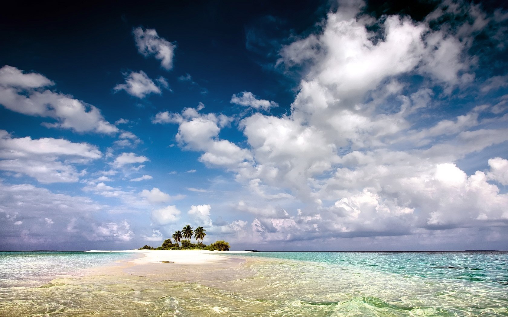 a piece of land desert island palm trees the waves of the sea the sky clouds the ocean landscape nature view