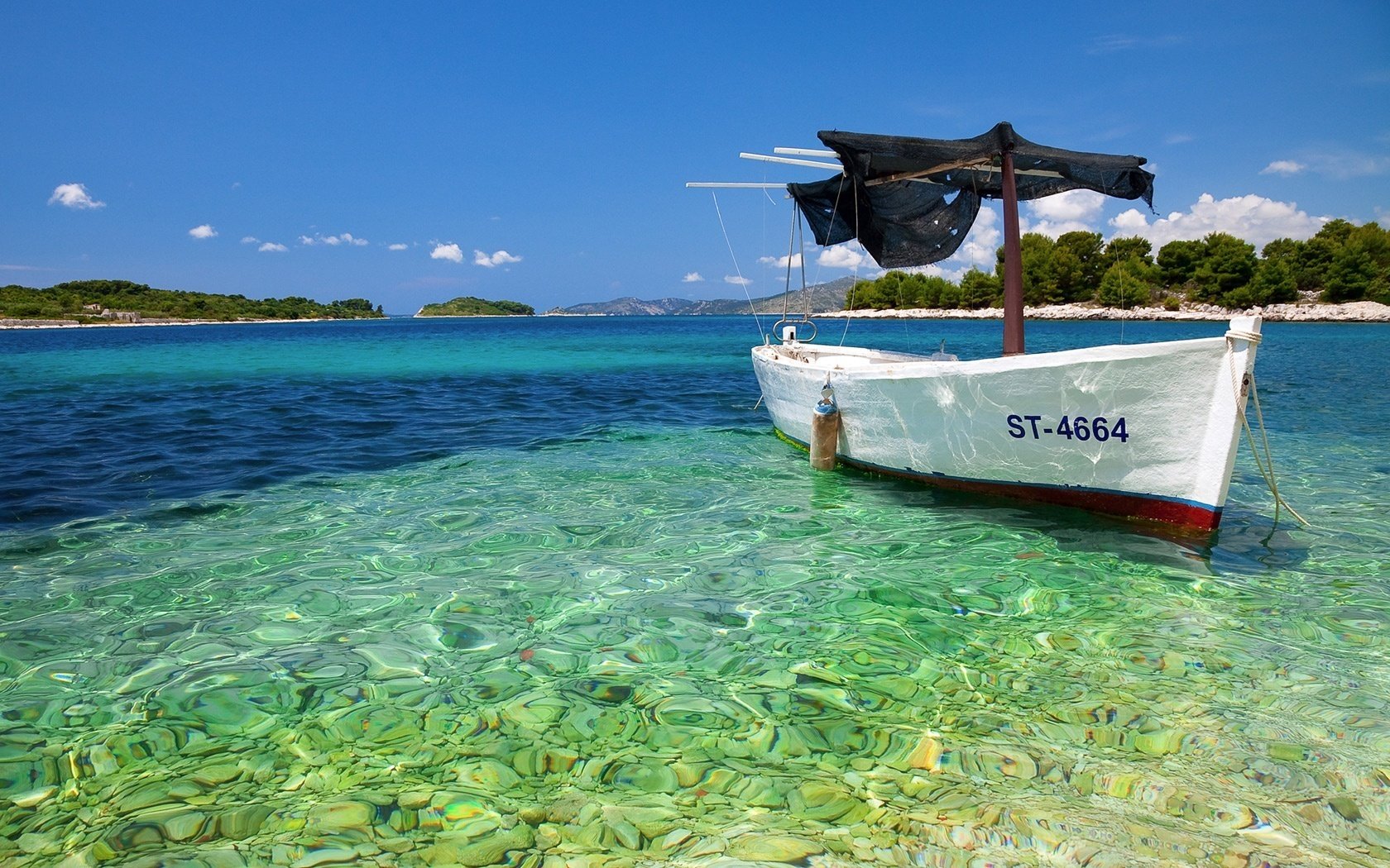 steiniger boden sonnenstrahlen boot wasser himmel berge küste meer boden steine türkis blau wolken sommer boot insel urlaub resort natur