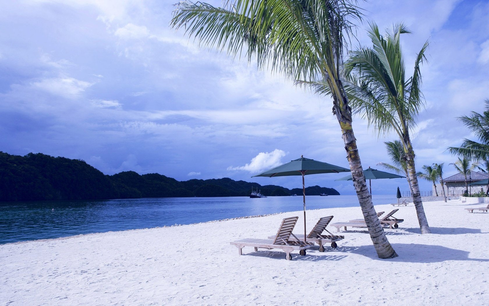 leerer strand liegen aus holz felsen strand wasser himmel palmen sonnenliegen sonnenliegen sonnenschirme berge ufer urlaub urlaub resort inseln tropen wolken schatten sommer