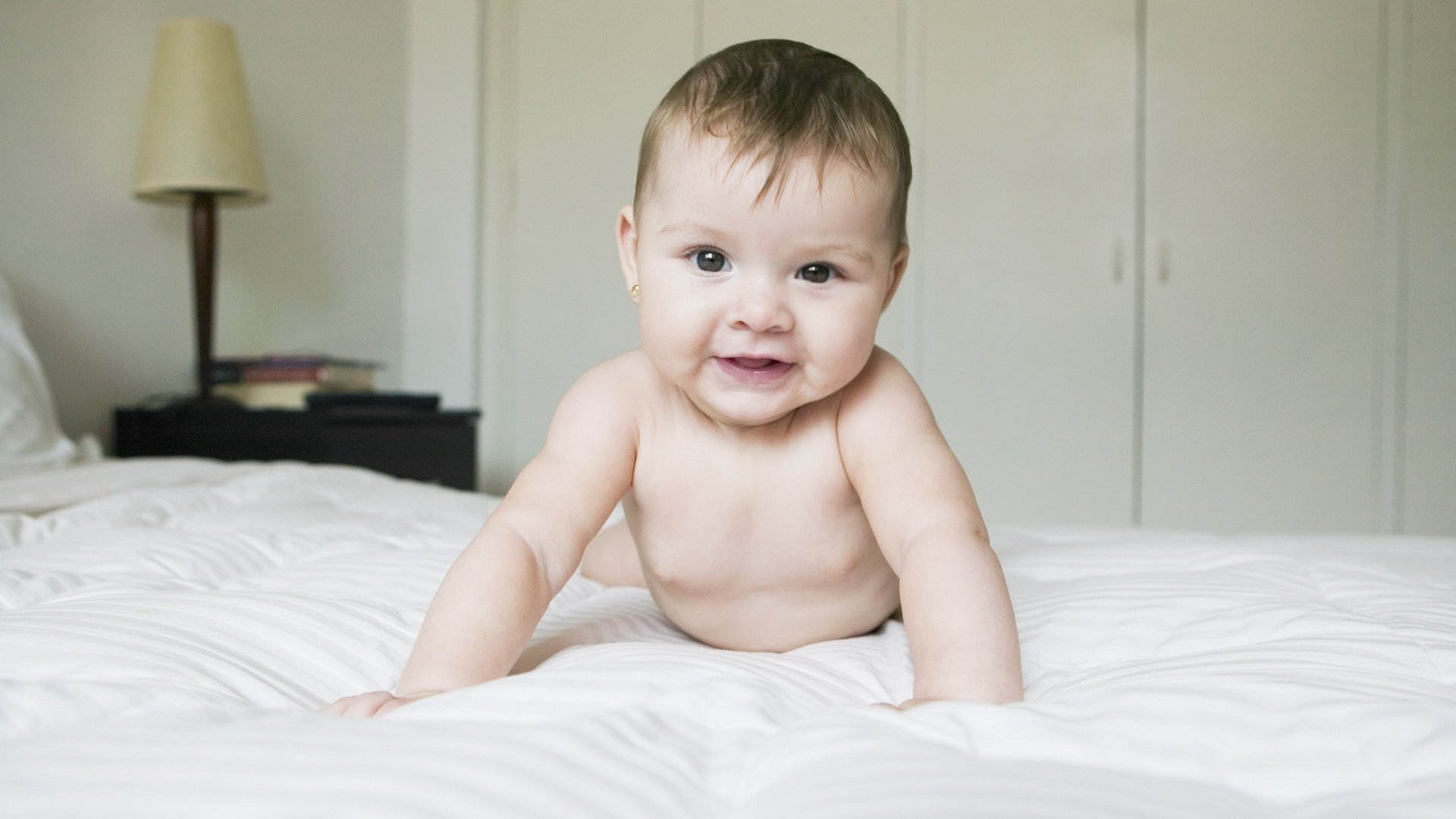 flauschige haare da bin ich dunkle augen porträt blick gesicht augen lächeln bett bett zimmer stehlampe bücher kind krümel baby krabbeln nackt