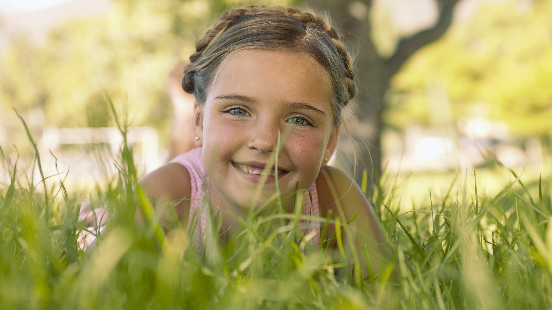 giace nell erba occhi scintillanti ragazza sorriso affascinante ritratto sguardo occhi sorriso viso ragazza trecce acconciatura umore estate verde gioia emozione lentiggini