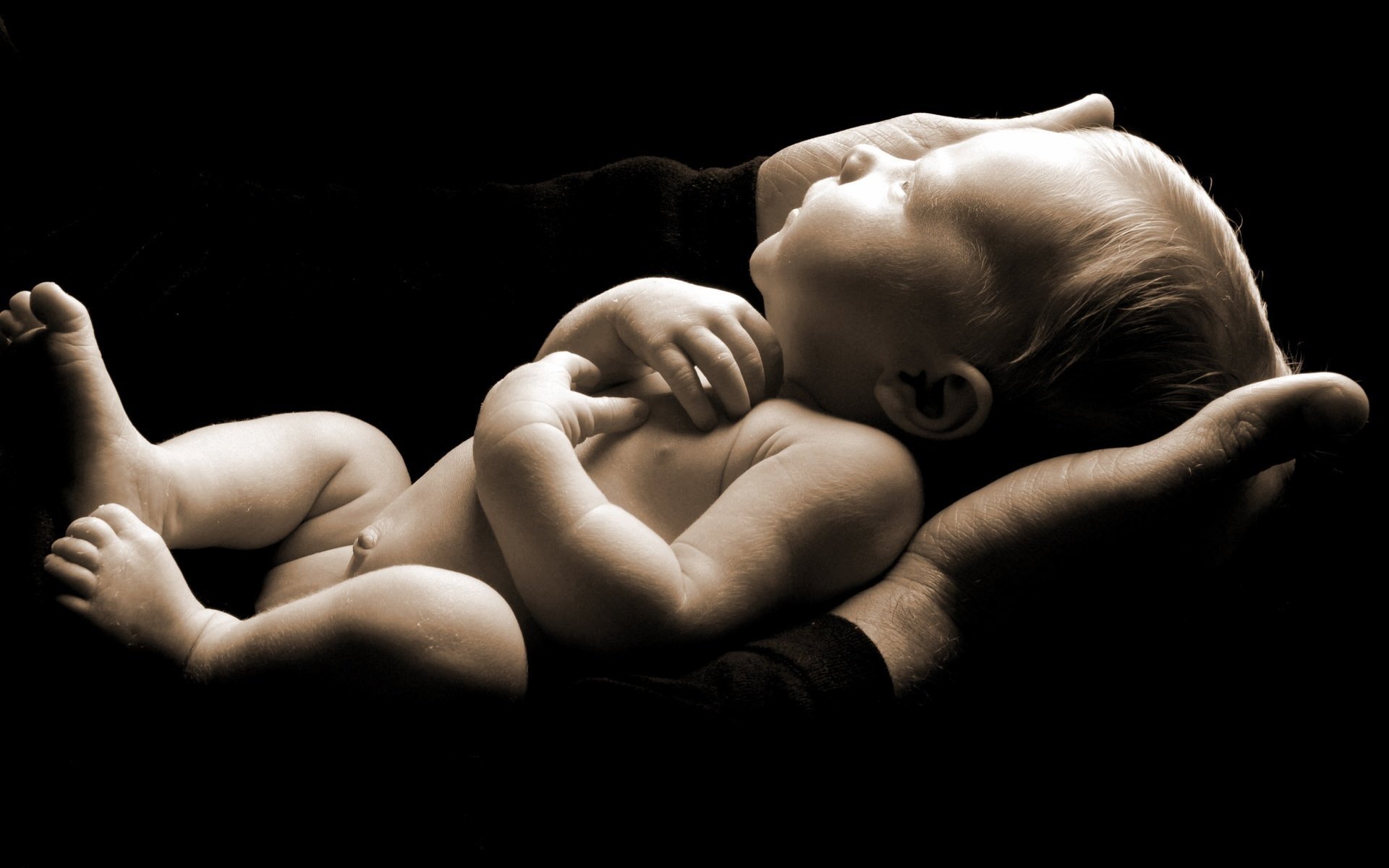 in the hands of a man a small creature trust a crumb a baby a baby a newborn a black background twilight