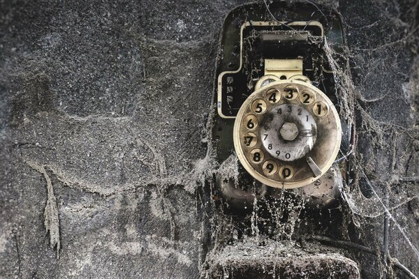 El Teléfono viejo montado en la pared está lleno de telarañas y suciedad
