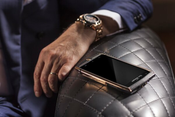 Золотые часы на руке и смартфон