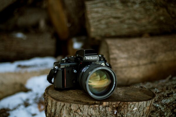 Nikon camera is lying on a stump