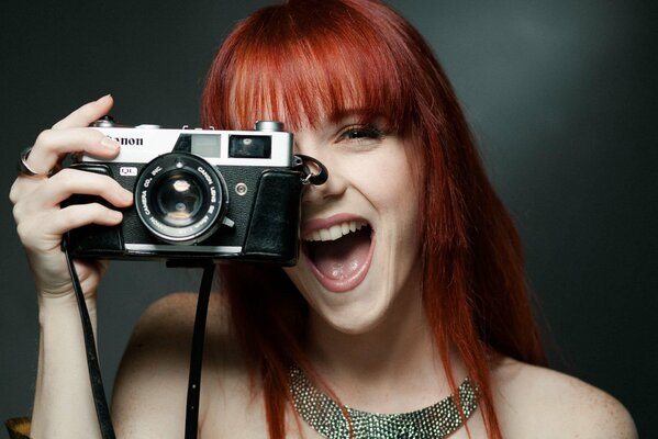 Laughing redhead girl with a camera