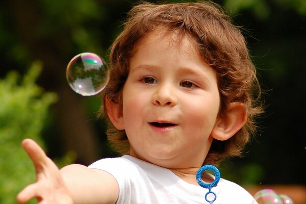 Niño sorprendido jugando con pompas de jabón