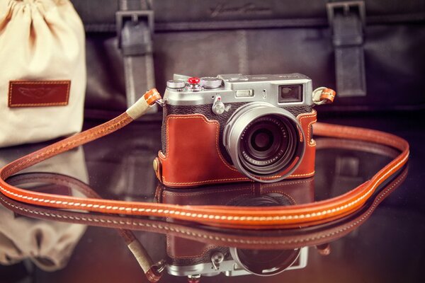 Piccola macchina fotografica sul tavolo trasparente con cinturino arancione