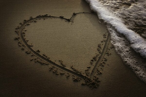A heart painted on the sand near the sea