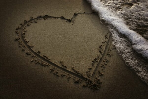 Cuore dipinto sulla sabbia vicino al mare