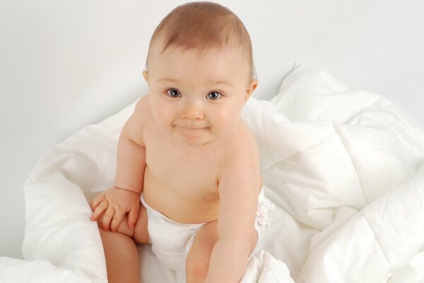 Süßes Baby auf einer weißen Decke in Windeln