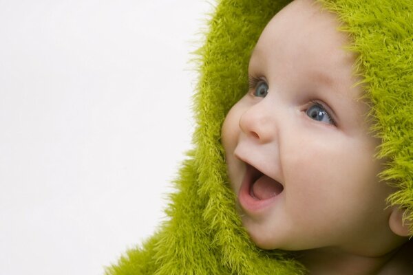 Bambino gioioso sorridente in copriletto verde