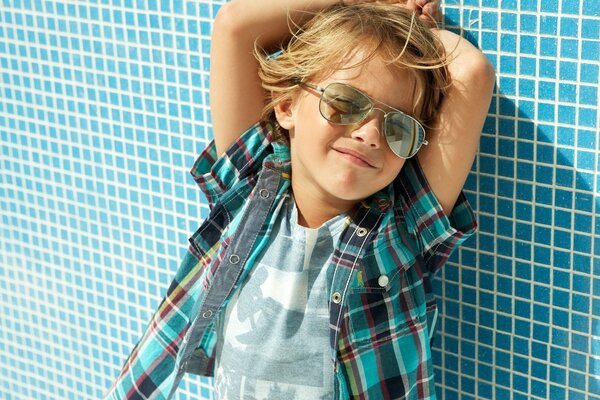 Chico con camisa a cuadros en la pared azul