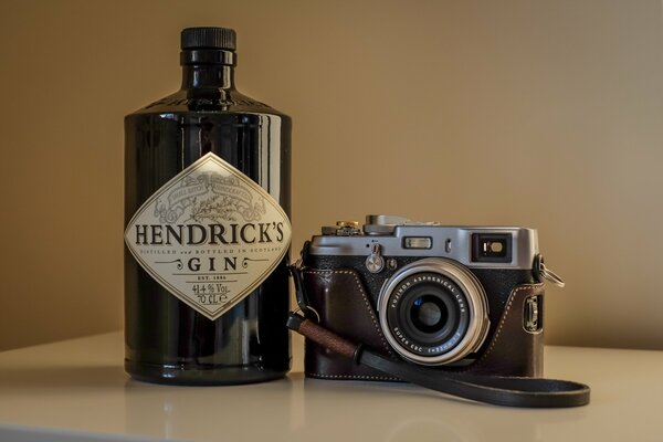 Fotocamera in una custodia sullo sfondo di una bottiglia di gin