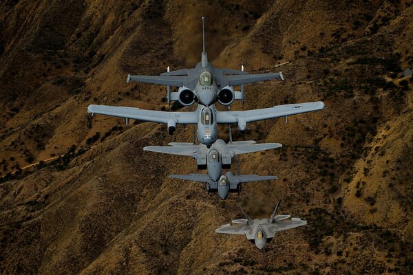 Aviones de combate f - 16, f -22, f -15 en el cielo sobre las colinas