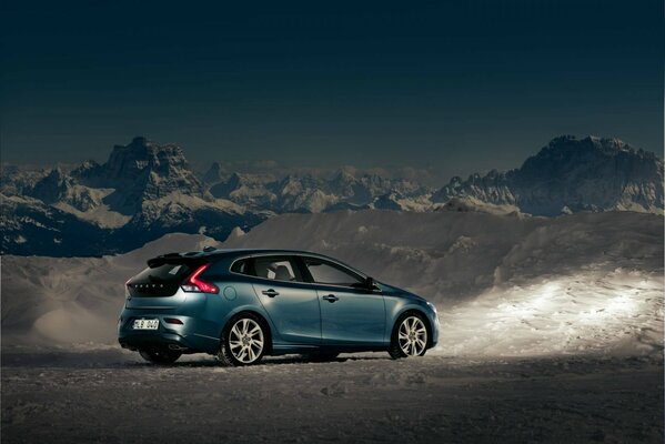 Voiture volvo au milieu des montagnes et de la neige au crépuscule