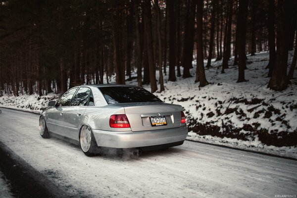 Authentique voiture Audi blanc au milieu de la forêt enneigée et de la route