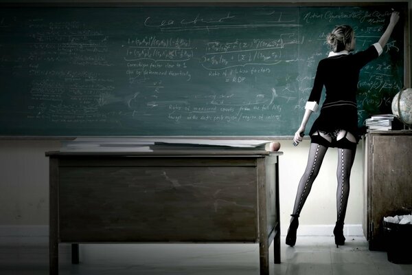 A teacher in stockings writes on the blackboard