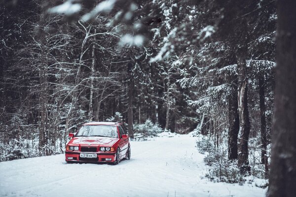 An old German car is driving through a snow-covered forest