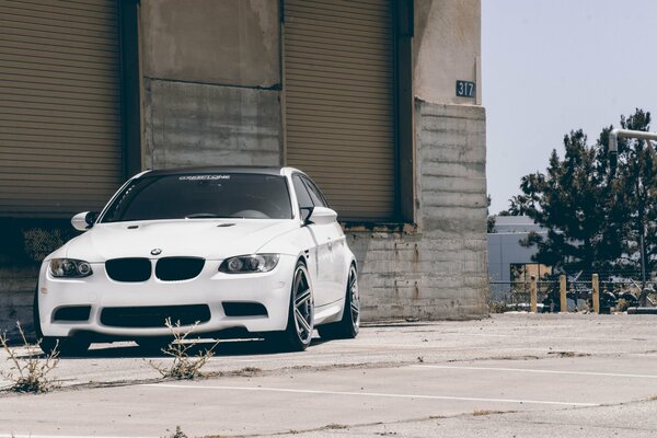 A white BMW with a black roof is standing around the corner