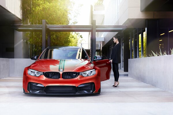 Ein rotes BMW-Auto neben dem ein Mädchen in Schwarz steht