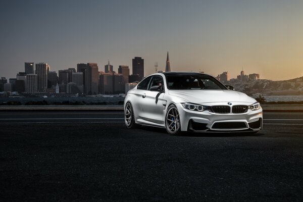 Bmw blanc sur fond de coucher de soleil urbain