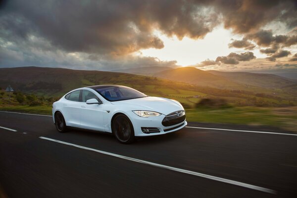 Tesla Model s blanc sur fond de routes, de collines et de nuages