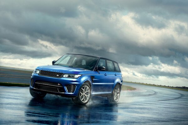 Bright blue range rover against the background of gathered gray clouds