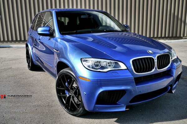 Blue BMW on the background of a gray fence