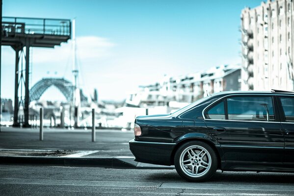 BMW e38 740il black is on the road side view rear half