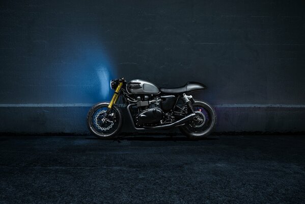 Чёрный мотоцикл возле синей стены