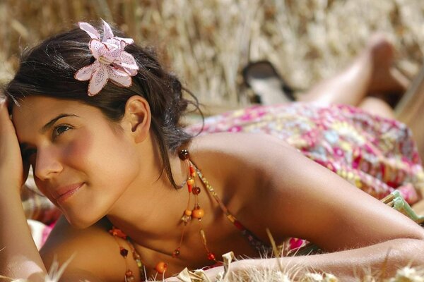 Piękna dziewczyna z kwiatem we włosach leży i wygląda kusząco. Motywy hawajskie
