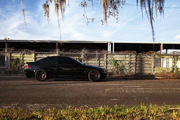 A black car is parked at the fence